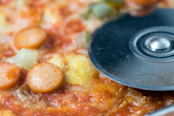 Pizza / Pizza topped with sausage, vegetables and cheese with a Pizza Cutter