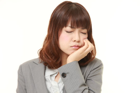 young Japanese businesswoman suffers from toothache