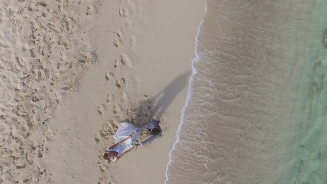 Just-married couple on a caribbean beach, wedding day - drone view
