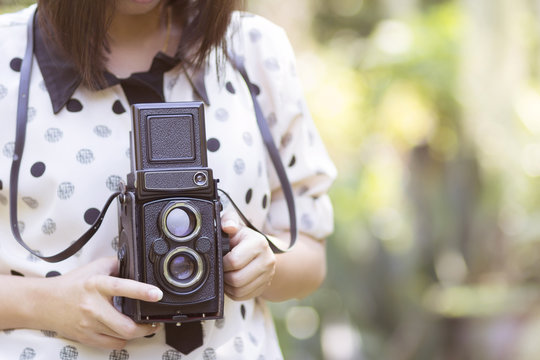 Woman using vintage camera taking photos in the garden.(Vintage effect style pictures)