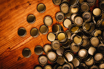Large pile of beer bottle caps on wooden desk