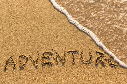 Adventure - word drawn on the sand beach with the soft wave.