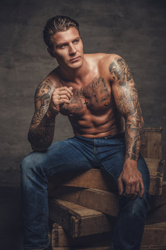 Shirtless tattooed guy in denim jeans.