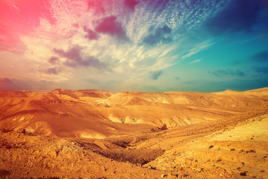 Mountainous desert with colorful cloudy sky. Judean desert in Israel at sunset
