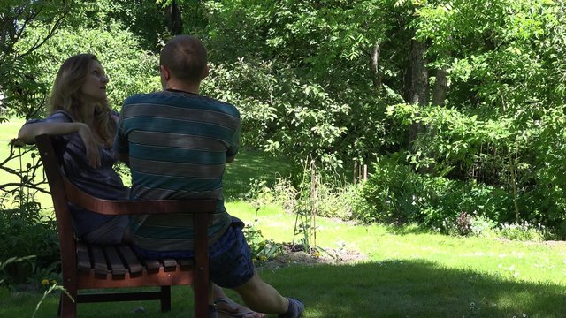 boyfriend and girlfriend relationship quarrel on bench in nature. Stressed man and woman. Static shot. 4K 
