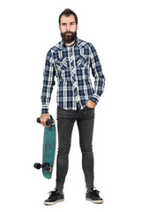 Funny hipster with carrying skateboard in one hand looking at camera. Full body length portrait isolated over white studio background.