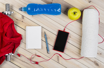 Sport Equipment. Barbell, Red Shirt, Isotonic Drink, Apple, Towel, Smart Phone With Earphones And Notebook To Workout Plan On Wooden Table. Sport Fitness Background