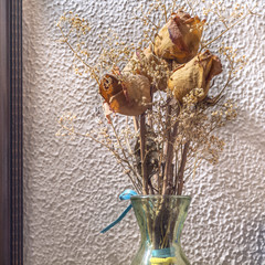 Bouquet of dried roses in front of a textured wall