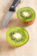 Eine halbierte Kiwi liegt auf einem Holzbrett
