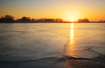 Winter landscape with lake and sunset sky.