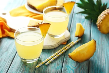 Crédence de cuisine en verre imprimé Jus Glasses of pineapple juice on a blue wooden table