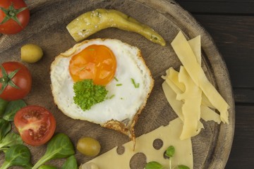 Fried Eggs on a wooden background. Fried eggs and vegetables on the cutting board. Homework healthy food.
