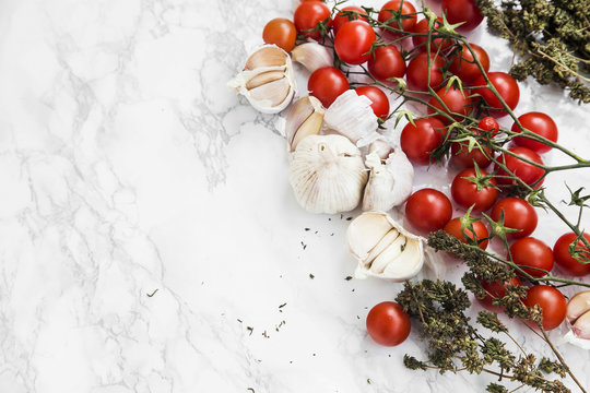 Cherry tomatoes, garlic, thyme herb on marble background