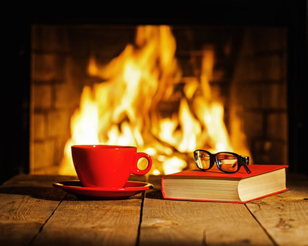 Red cup of coffee or tea, glasses and old book on wooden table n