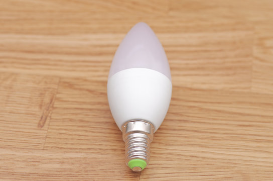 LED candle E14 lamp on the wooden background