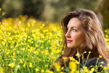 Beautiful young girl among yellow flowers