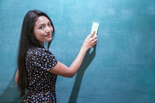 woman in a dress cleans a blackboard