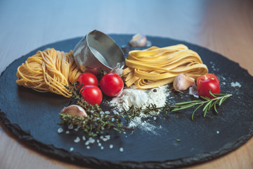 Beautiful fresh spaghetti on the blackboard with spices and tomatoes
