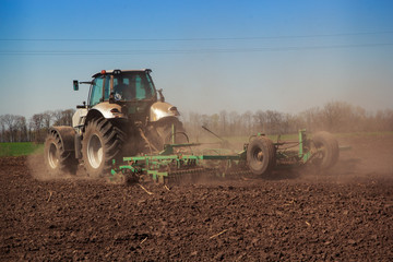 tractor cultivator raises great dust on soil