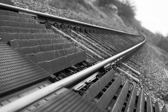 Train tracks. An angled, black and white DSLR photo of train tracks stretching into the distance.