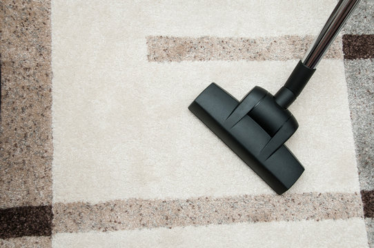 Close up of vacuum cleaner nozzle cleaning carpet at home