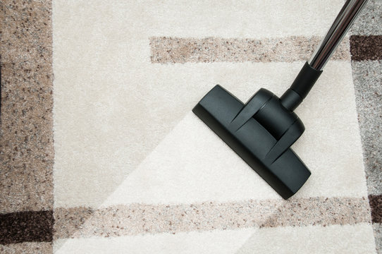 Close up of vacuum cleaner nozzle cleaning carpet at home