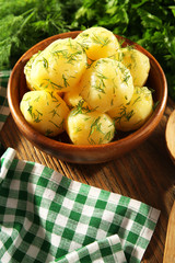 Boiled potatoes with greens in bowl on table close up