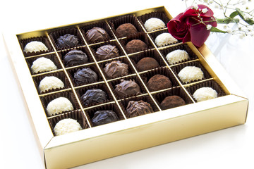 Truffles in box with red rose on white background 