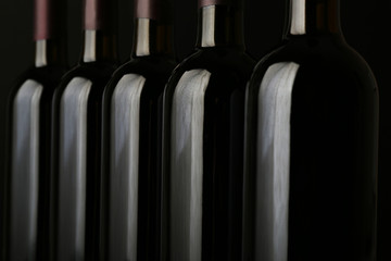 Wine bottles in a row on black  background, close up