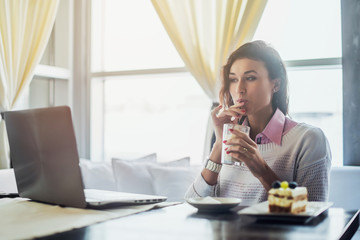 Woman drinking coffee working on laptop in cafe, morning breakfast