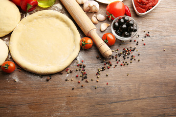 Dough basis and ingredients for pizza, on the table