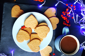 Fototapeta na wymiar Heart shaped biscuits on plate and mug on a table, top view