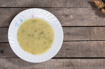 Jerusalem artichoke soup in plate on wooden background with copy space