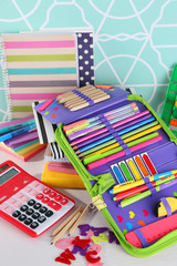 Pencil case with various stationery on wooden table, close up