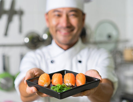 Smiling asian chef with sushi. Focus on sushi