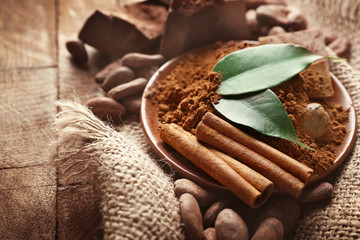 Bowl with aromatic cocoa powder and green leaf on a sacking, close up