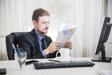 serious businessman sitting at his desk and  read business documents 