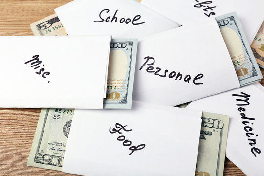 Distribution of money, financial planning, dollars in envelopes, on wooden table background