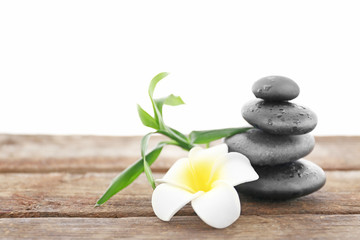 Fototapeta na wymiar Spa stones with bamboo and tropical flower on white background