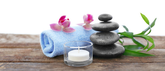Spa stones with towel, candle, bamboo and purple orchids on white background