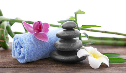 Fototapeta na wymiar Spa stones with towel, tropical flowers and bamboo on white background