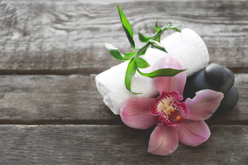 Spa stones with towel, pink orchid and bamboo on wooden background