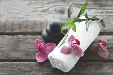 Spa stones with towel, bamboo and purple orchids on wooden background