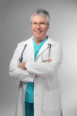 A handsome doctor with crossed arms standing on grey background