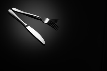 Stainless steel, modern silverware on black background with reflection.