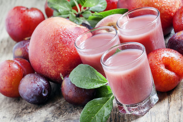 Plum and peach juice with pulp, spilled red and blue plums and p