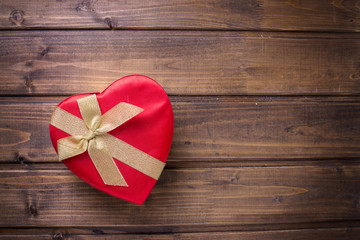 Festive gift box with bow on  dark wooden background.