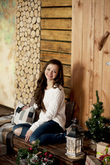 Young beautiful happy woman in sweater and blue jeans sitting on floor at home