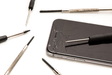 Broken smartphone and small screwdrivers for repair