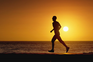 Fototapeta na wymiar Silhouette Man running on the beach at sunset